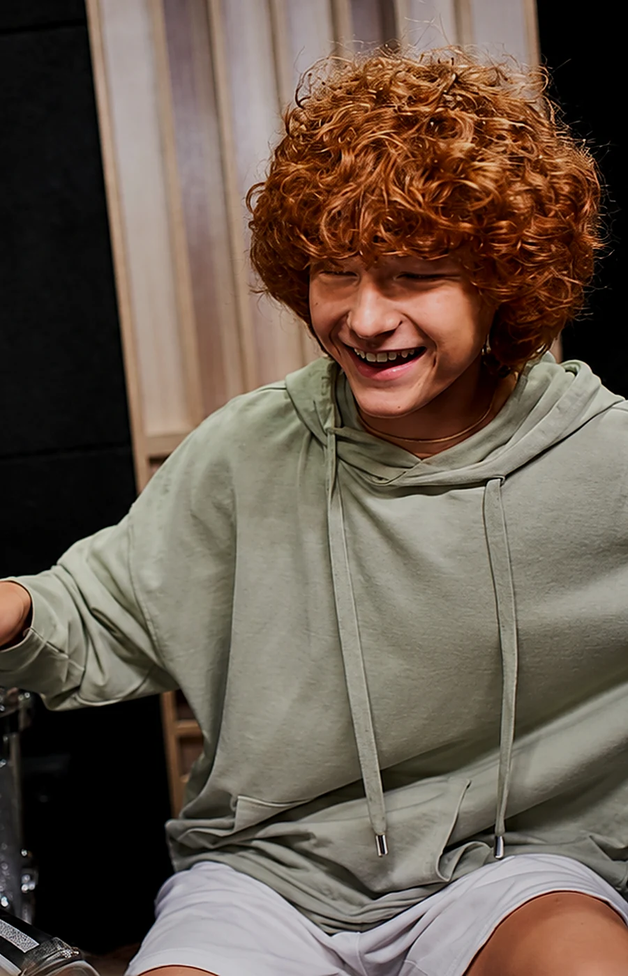 Uśmiechnięty nastolatek grający na perkusji w studiu